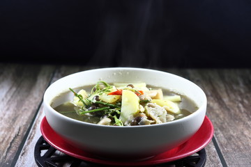 Traditional spicy soup of mixed fresh mushroom, chopped sweet potato, chilly and local herbal vegetable in the bowl. Famous hot and spicy ancient vegetarian menu in Thai restaurant.