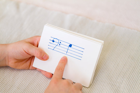 Young child practices naming music notes with flash cards; Young child memorizes musical notes