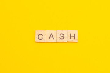 Fototapeta na wymiar Word CASH made from wooden cubes on yellow background. Business concept
