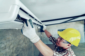 Male technician cleaning air conditioner indoors