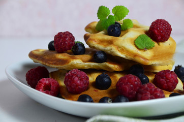 Homemade Belgium Waffles with fresh blueberries for breakfast. White plate, Viennese waffles with raspberries and mint. quick delicious breakfast on white background