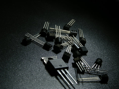 Macro shot of silicon power transistors on a black surface.

