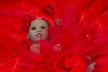 portrait of a newborn doll girl in red