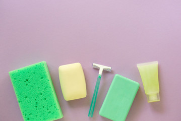 Flat lay of bath and hygiene products. Razor, soap bar and washcloth on a lilac background. Space for text
