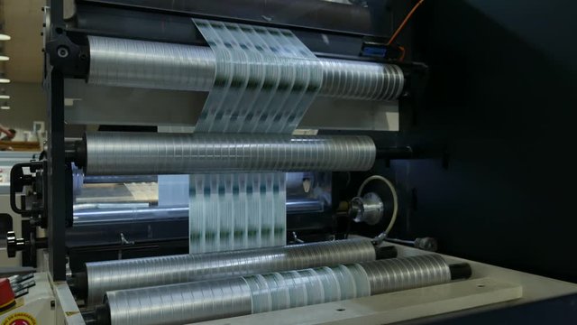 label machine working fast, rolls and ink do their job, red product labels are made in a chain in a labeling factory