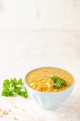 Pea soup with pieces of bacon and parsley in blue bowl on a white background.