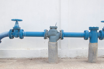 Large water supply valve with a white background of the cement wall
