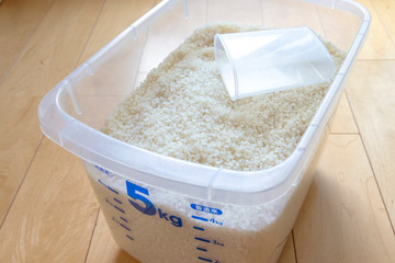 透明なプラスチックの米びつと計量カップ