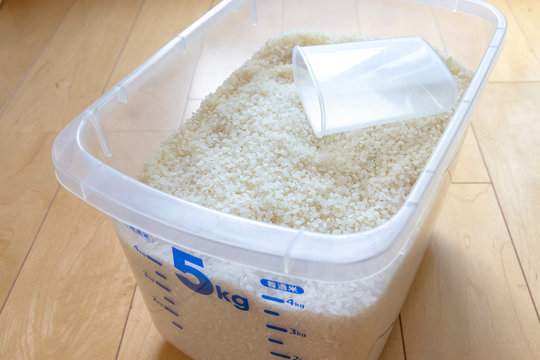 a plastic container filled with a mixture of white rice - 透明なプラスチックの米びつと計量カップ