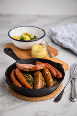 Oldenburger Grünkohl mit Pinkel, Kohlwurst, Kassler Schweine Nacken, Senf und Kartoffeln in Gusseisen Pfanne auf Marmor Tisch