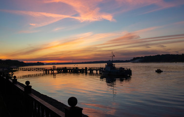 Fototapeta premium Small boat at the river pier against the background of the sunset