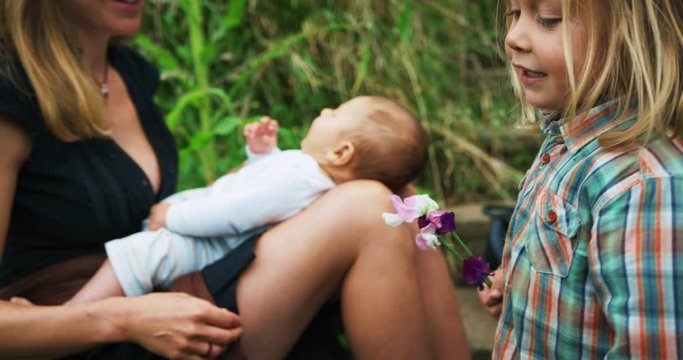 Mother with preschooler and baby relaxing in vegetable gardne