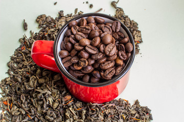 Dry green tea leaves and roasted coffee beans in a red mug. Close-up view from above. The concept of coffee or green tea.