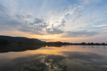 Obraz na płótnie Canvas 池の水面に映り込む朝日と雲