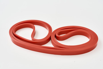 Naklejka premium Elastic expander. Red resistance band for fitness isolated on grey background