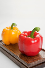red and yellow bell peppers(paprika) on wooden tray