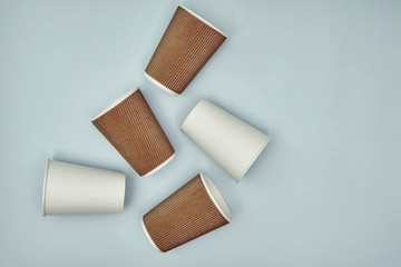 Paper cup in hand on a colored background. Eco-friendly materials in a coffee shop, biodegradable disposable tableware. Close up.