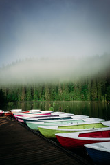 Vertical portrait of colorful boats at shore. Morning landscape from Red Lake, Romania