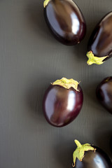 Raw Purple Eggplants on a black surface, top view. Flat lay, overhead, from above. Copy space.