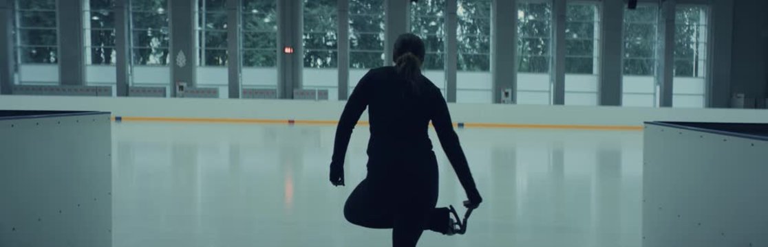 TRACKING Professional female ice figure skater entering the rink. Shot on RED cinema camera with 2x Anamorphic lens