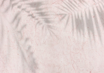 pastel pink textured Japanese paper background with palm leaves overlay shadow