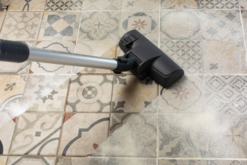 cleaning and removing dust on kitchen floor with vacuum cleaner.