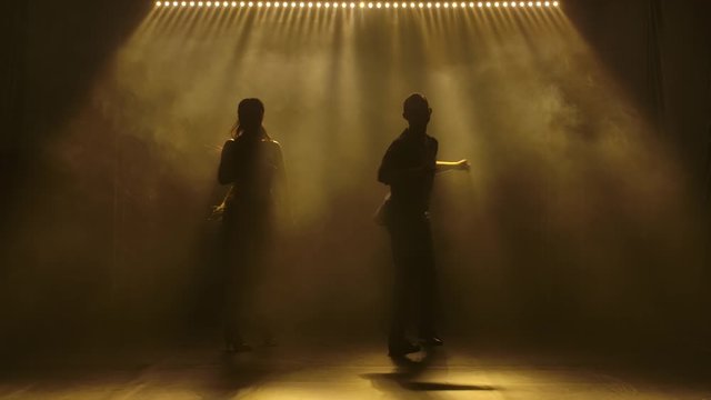 Young couple dancing latin music. Bachata, merengue, salsa. Shot in a dark studio with neon lights in the background.