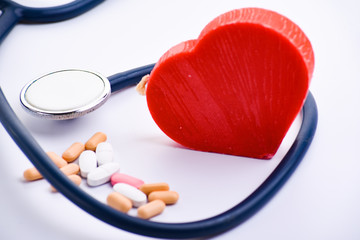 Medical stethoscope, pills and red heart on white background. Cardiology concept