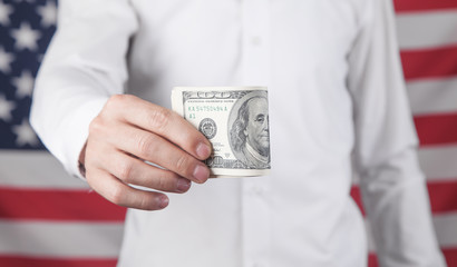 Man showing dollars on the background of American flag.