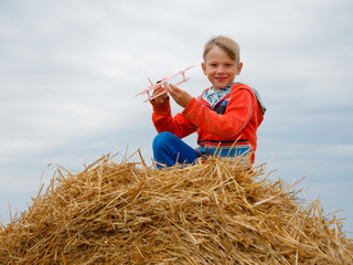 Naklejka na ściany i meble boy in the field playing with a toy airplane