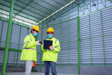 Asian Industrial Engineer in Hard Hat Wearing Safety Jacket plan work with warehouse workers Processes in the factory.