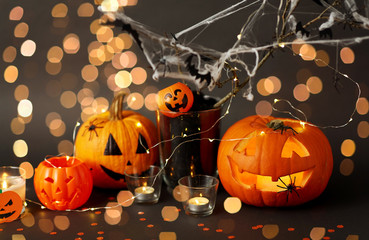 halloween and holiday decorations concept - jack-o-lantern or carved pumpkin, burning candles,...