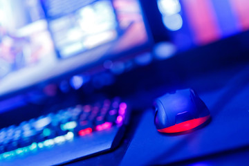 Professional computer mouse for video games and cyber sports on background of monitor, neon color