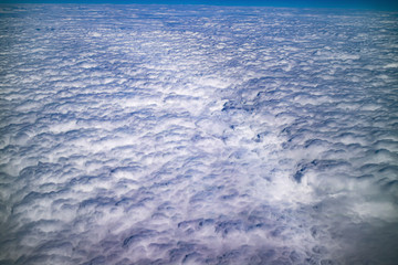 Floating clouds in the blue sky, view from airplane