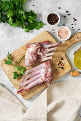 Raw ribs of a young lamb. Raw lamb ribs in a black ceramic plate on the black kitchen table. Raw meat of a young lamb on the table	