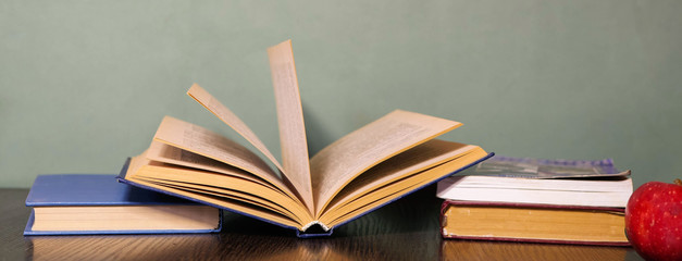 Stationary and books lay on the table. Studying process. Glasses for reading. Back to school. Green chalkboard. 