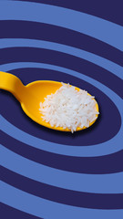 rice seed in yellow spoon on blue circles pattern background colors.