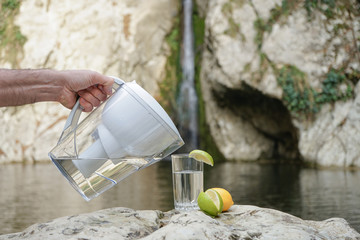 Water Pitcher. A man uses a jug with a filter to purify water against the background of a mountain...