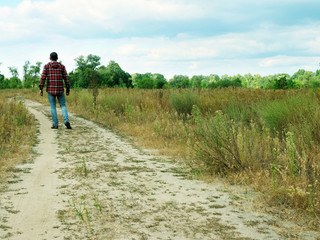 A tourist walks along a path in an autumn field. Tourism and searches.
