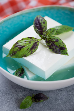 Blocks Of Feta Cheese In A Brine With Fresh Green Basil, Closeup, Selective Focus, Vertical Shot