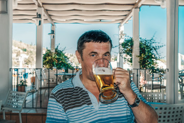 Fototapeta premium man drinks light beer sitting at a table in a cafe. Close up