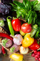 Assortment of vegetables in a basket on the table. A lot of different raw vegetables in the basket. Eggplant, tomatoes, garlic, sweet pepper, onion on the table. The concept of healthy eating