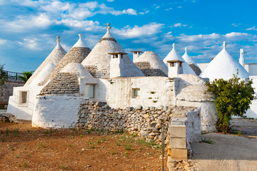 Fototapeta na wymiar Group of beautiful Trulli, traditional old houses and old stone wall in Puglia, Italy