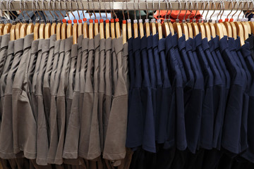 Men's polo shirts of different sizes on hangers.