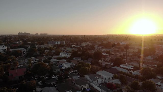 Aerial fly over in Culver city neighborhood, during sunset, with mountains in background in Los Angeles, California, USA