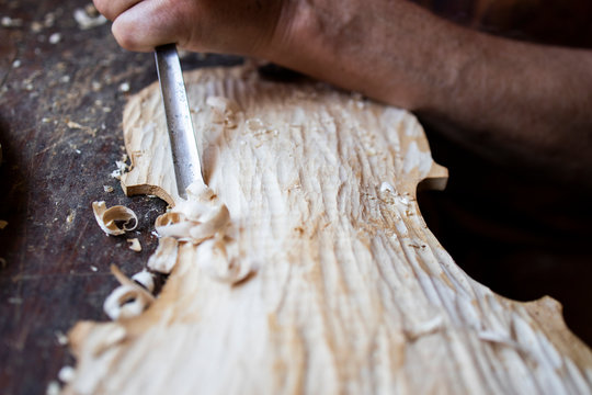Close up view of carpenter's hands carving wood in carpentry workshop. Woodworker working on his project.