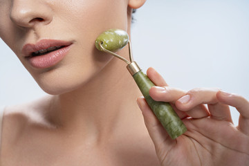 Relaxed lady holding a jade roller with one hand