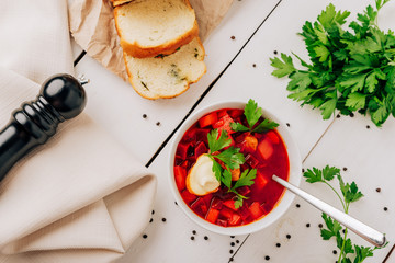 Borscht with fresh bread on a natural wooden background. Red beetroot soup with fresh bread