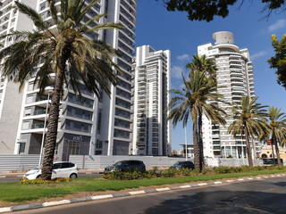 Fototapeta na wymiar HOLON, ISRAEL. August 05, 2020. A view of a newly built Holon neighborhood from Golda Meir street. New tall residential houses, palm trees, day, Israel real estate market concept image.