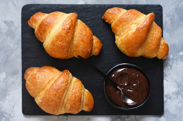 Croissants on a stone board on a concrete background. View from above.